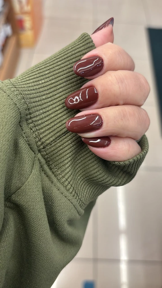 Unhas em tom bordô sobre uma manga verde
